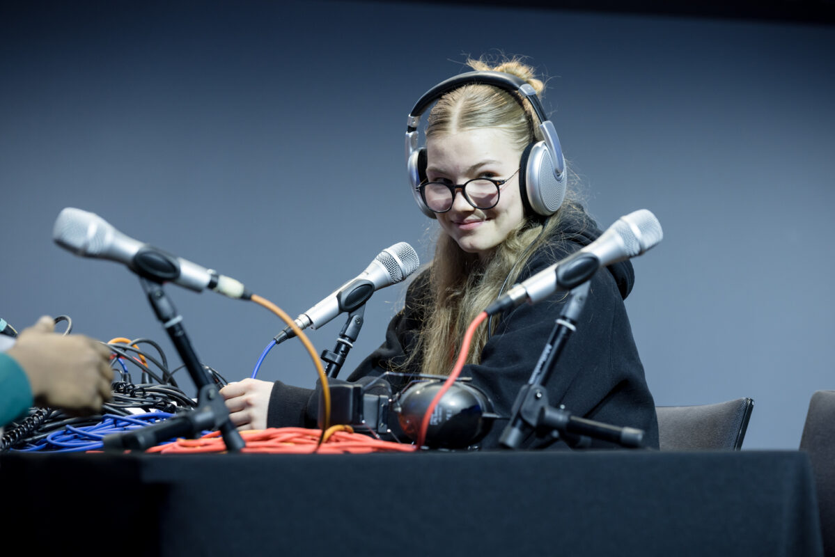 Eine junge Frau sitzt lächelnd am Radiopult